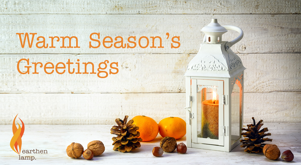 White lantern on table with fir cones. Text reads Warm Season's Greetings